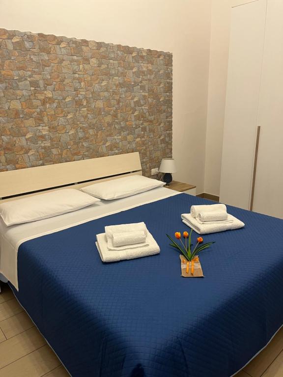 a bedroom with a blue bed with towels and flowers on it at Casa Carruvedda in Avola