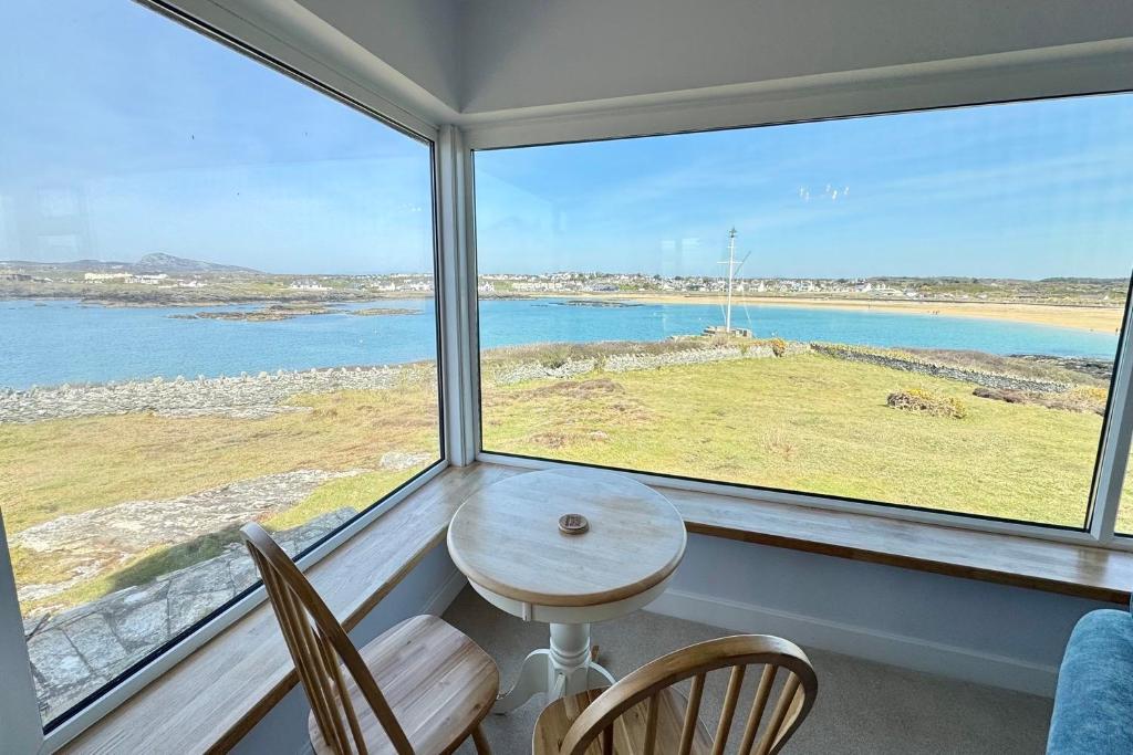a table and chairs in a room with a large window at AEL-Y-BRYN-5 BED- DRAMATIC SEA VIEWS - Sleeps 12 in Trearddur