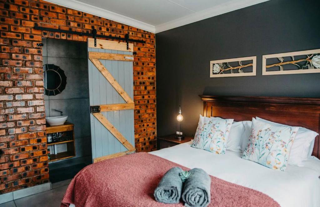 a bedroom with a bed and a brick wall at Adriaan Place in Bethlehem
