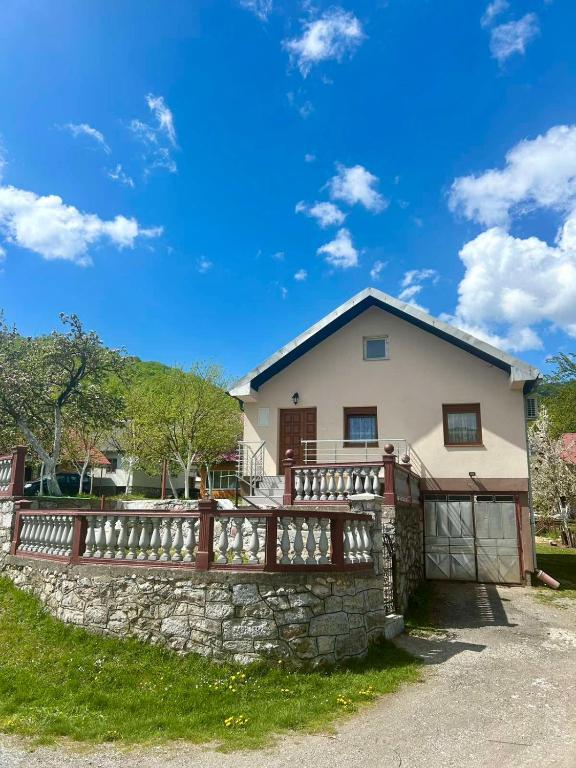 a house with a fence and a stone wall at Mont Peak Apartment in Kolašin