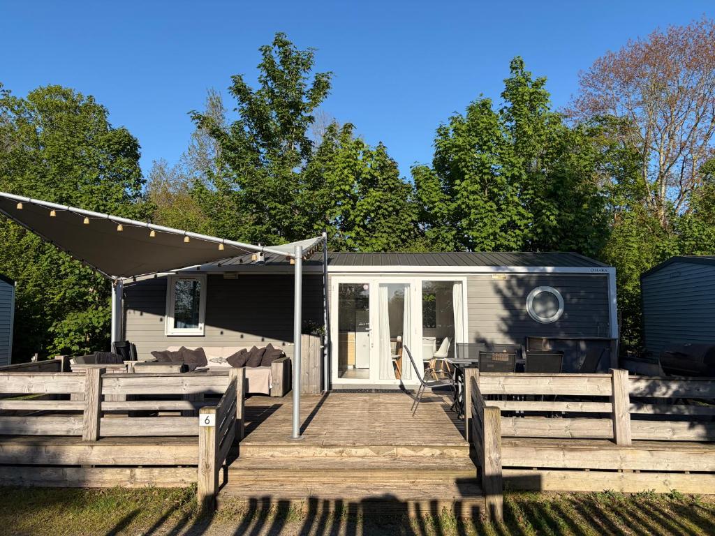 a tiny house with a porch and a deck at Chalet Masion Meerwijck 6 aan het Zuidlaardermeer in Kropswolde