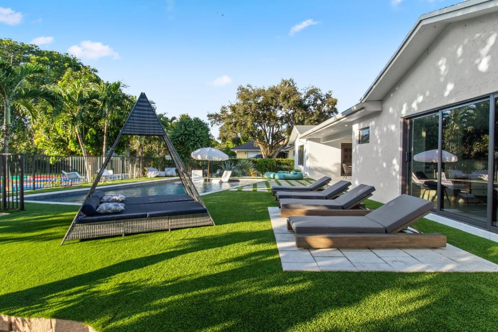 a yard with lounge chairs and a swimming pool at Platinum Villa w Karaoke, Pickleball, BKB & Soccer in Davie