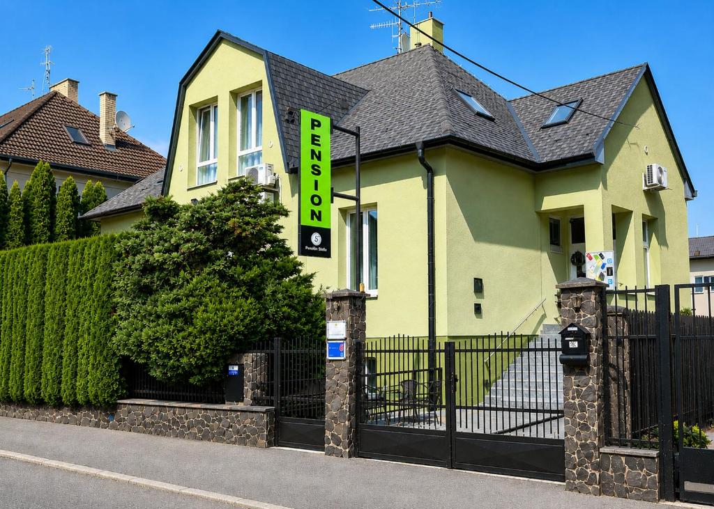 a yellow house with a gate with a sign on it at Penzión Tiberia in Trenčín