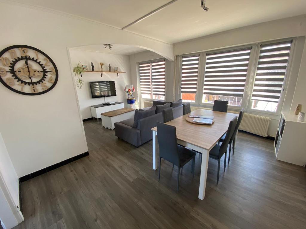 a dining room and living room with a table and a clock at Maison cosy Dunkerque in Dunkerque
