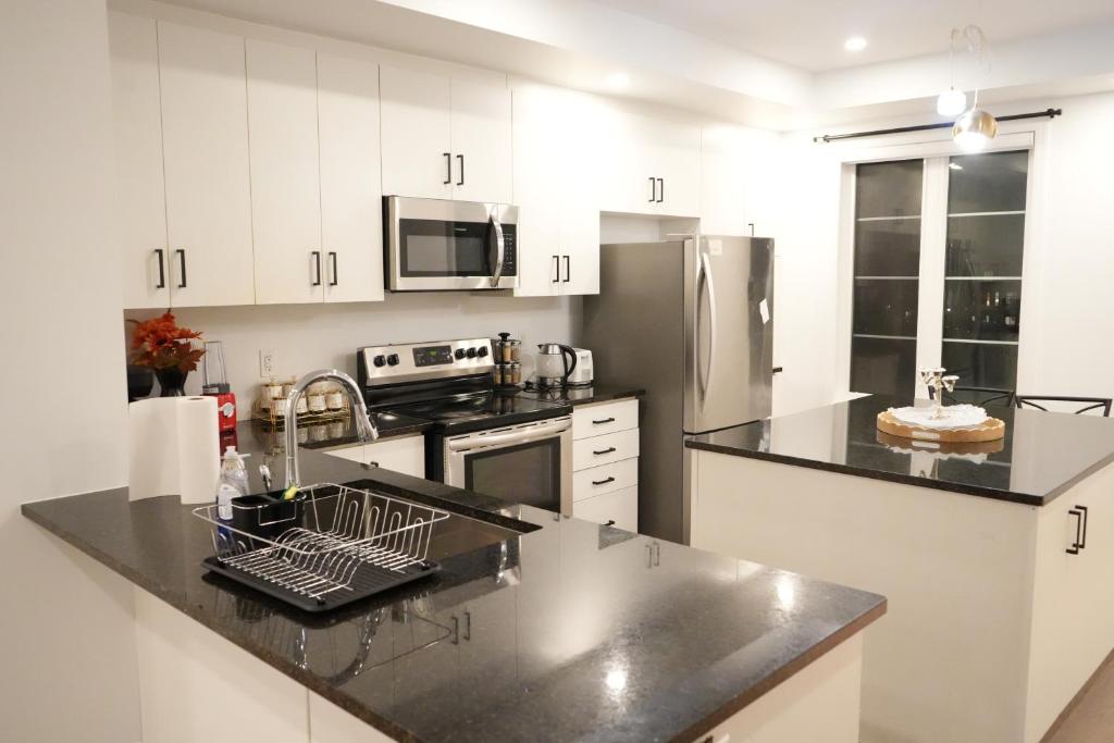 a kitchen with white cabinets and a black counter top at Charming Oakville Getaway in Oakville