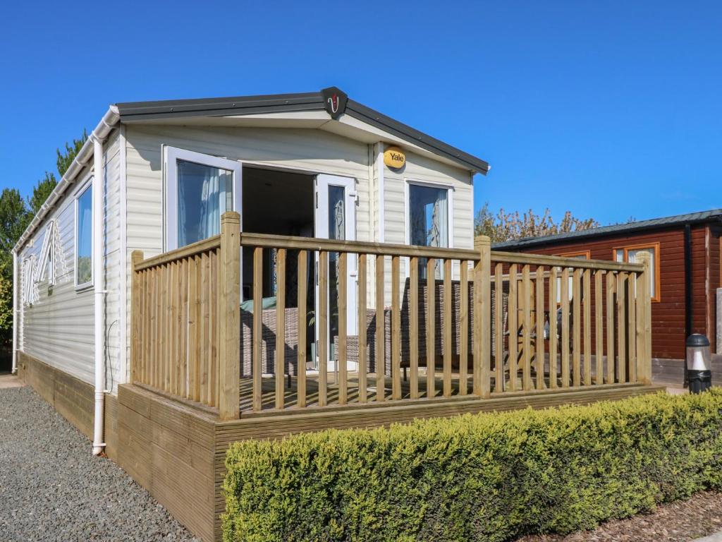 a tiny house with a wooden porch and fence at Plot 42 in Carlisle