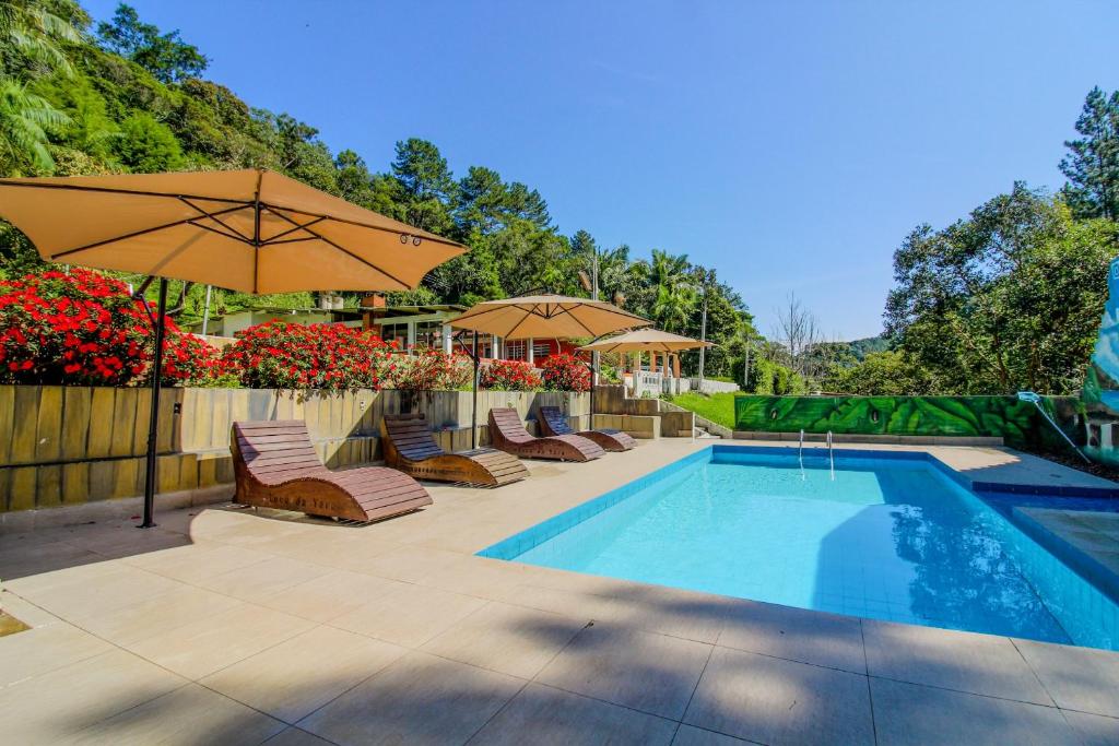 a swimming pool with chairs and umbrellas next to a fence at Sítio com Piscina Aquecida 7 Quartos com ar condicionado próximo de São Paulo in Juquitiba