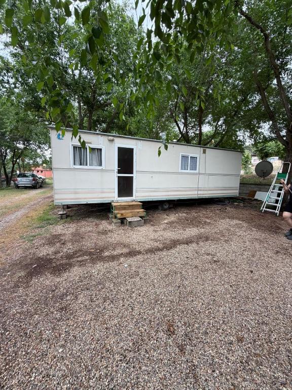 a large white trailer sitting on top of a gravel lot at Sid's mobile home - Camping Riba Roja in Riba-roja d'Ebre