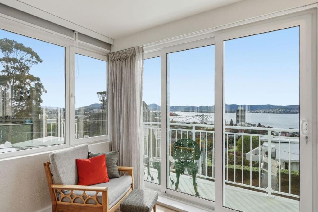 a living room with large windows and a chair with red pillows at Designer Stay with River Views) in Sandy Bay