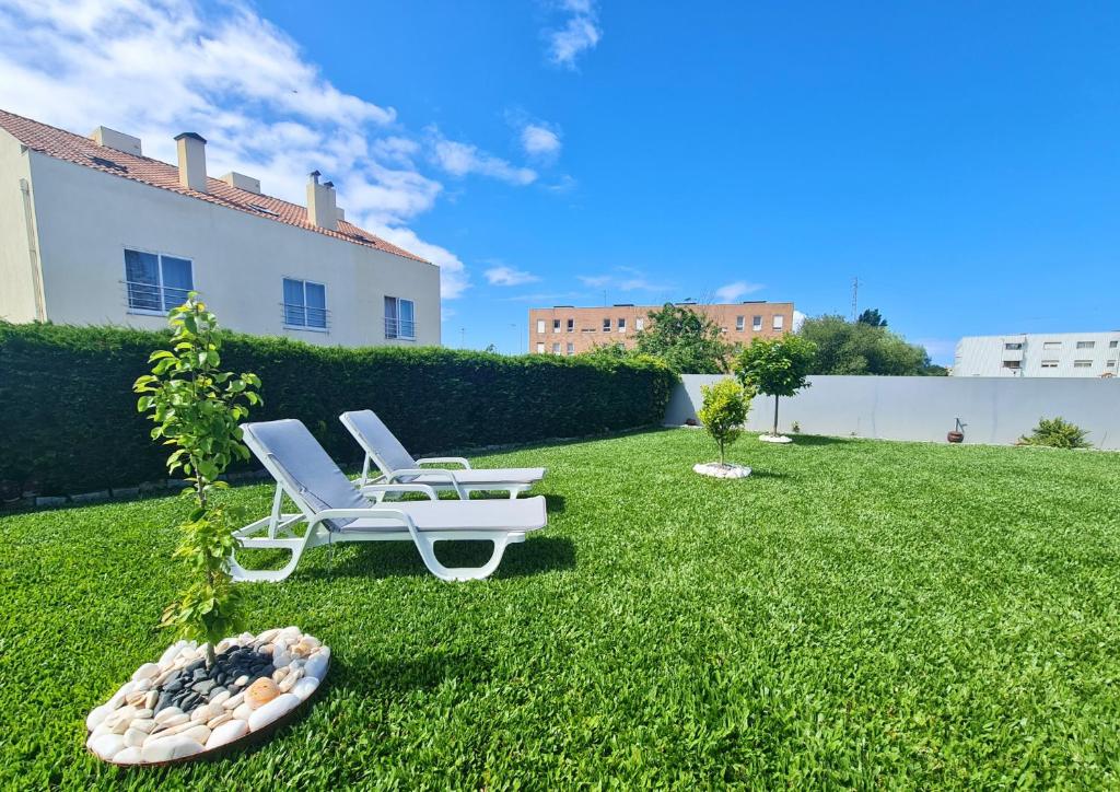 a lawn with two lounge chairs and a plant at Casa do Telhal in Vila Nova de Gaia
