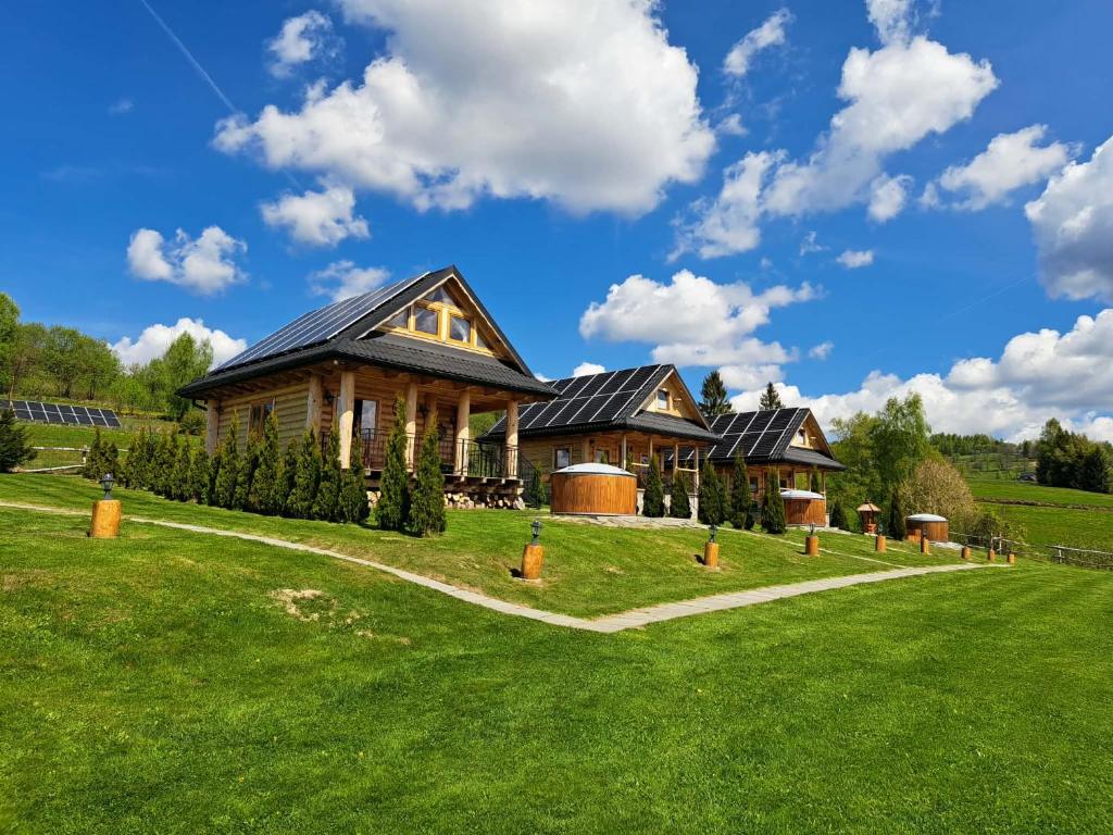 a house on a hill with a green lawn at Domki Gorce Klikuszowa Sauna Jacuzzi in Klikuszowa