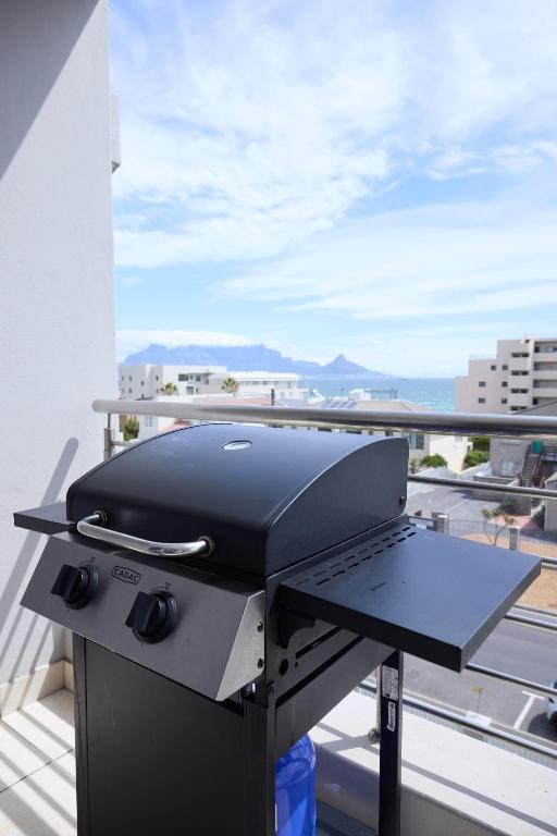 a grill on a balcony with a view of the ocean at 2 Bedroom Bloubergstrand Apartment with Ocean Views in Bloubergstrand