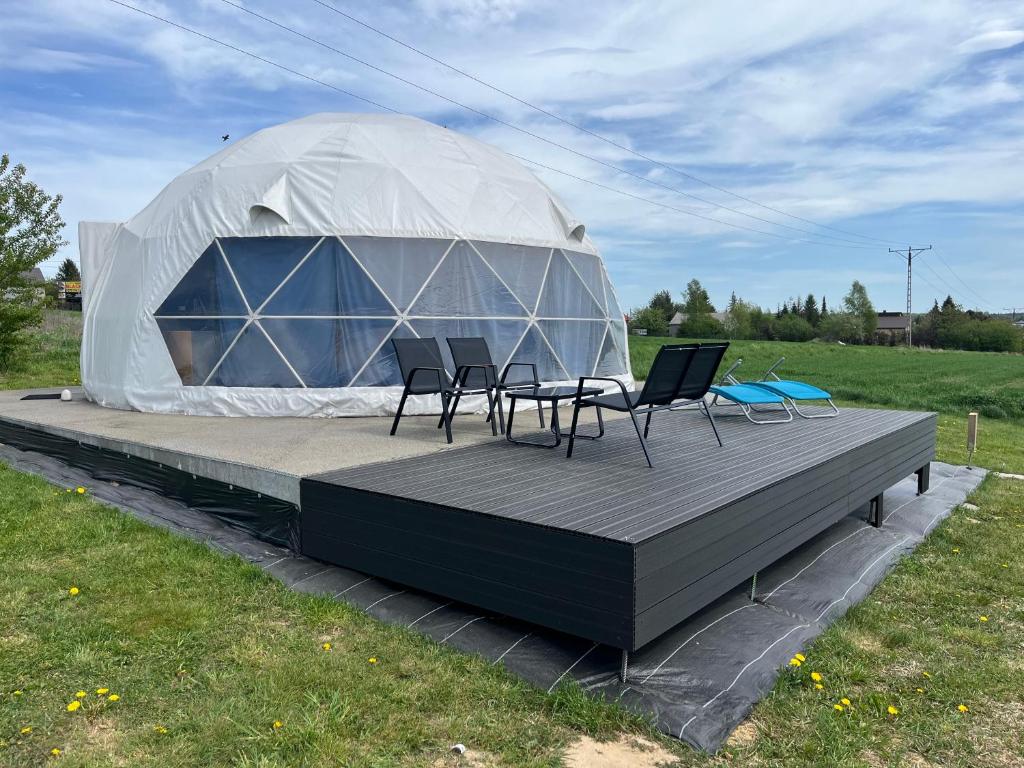 a tent with chairs and tables in a field at Glamp Ojcowska in Jerzmanowice
