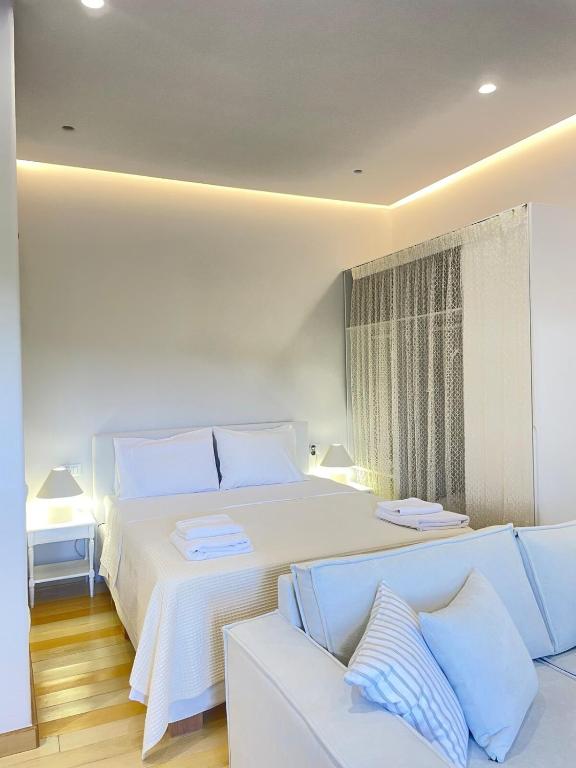 a white bedroom with a white bed and a couch at Small home Pyrgos in Panormos
