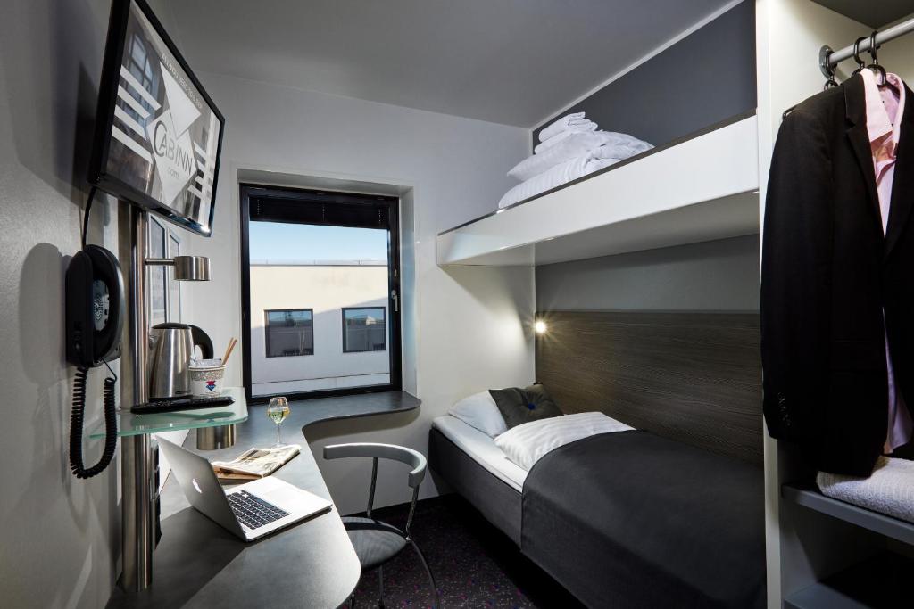 um pequeno quarto com 2 camas e uma janela em Cabinn Aarhus em Arhus