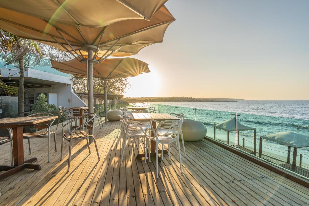 a wooden deck with tables and umbrellas on the water at Hotel Tropical Inn in Tierra Bomba