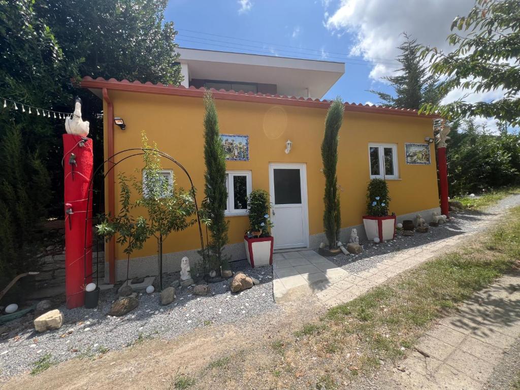 a small yellow house with potted plants in front of it at Cosy Tiny House Centro Vila Real in Vila Real