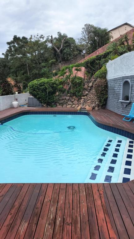 a large blue swimming pool on a wooden deck at Protea House - self-catering house with a Pool in Durban