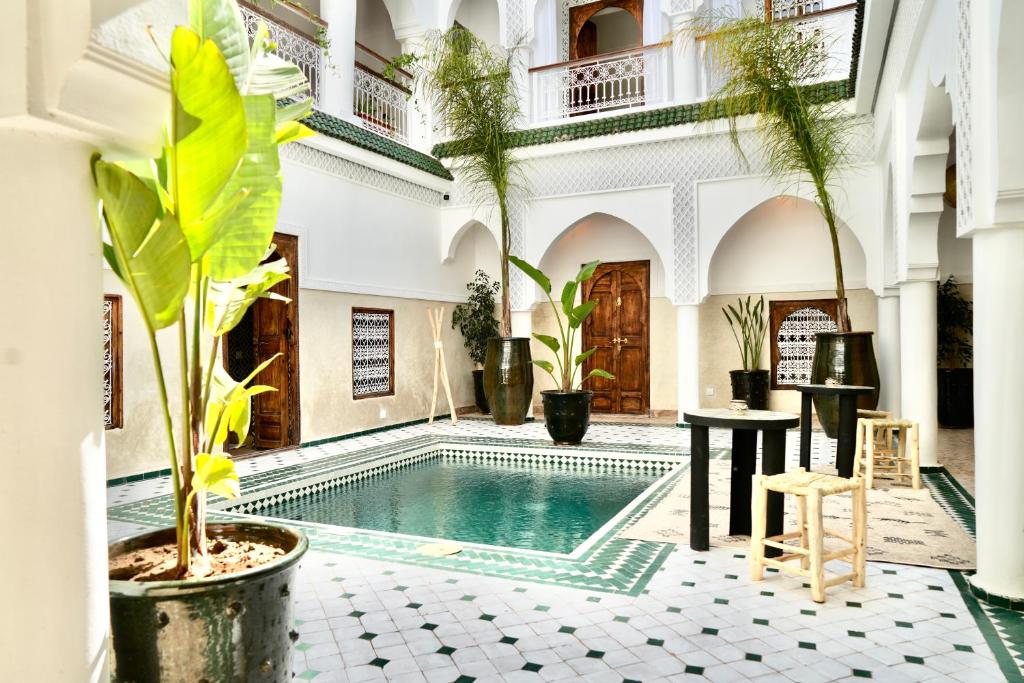 a courtyard with a pool in a building with plants at Riad Aura Suites & Spa in Marrakesh