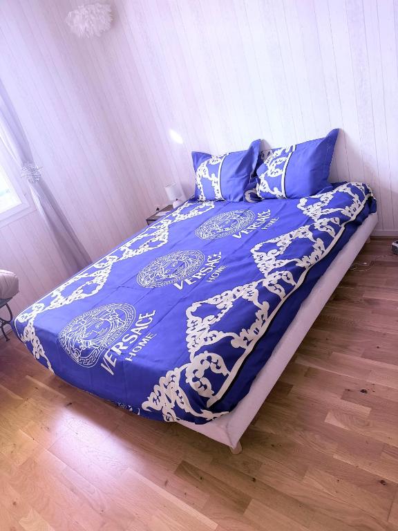 a bed with a blue and white blanket and pillows at Orléans passe in Olivet