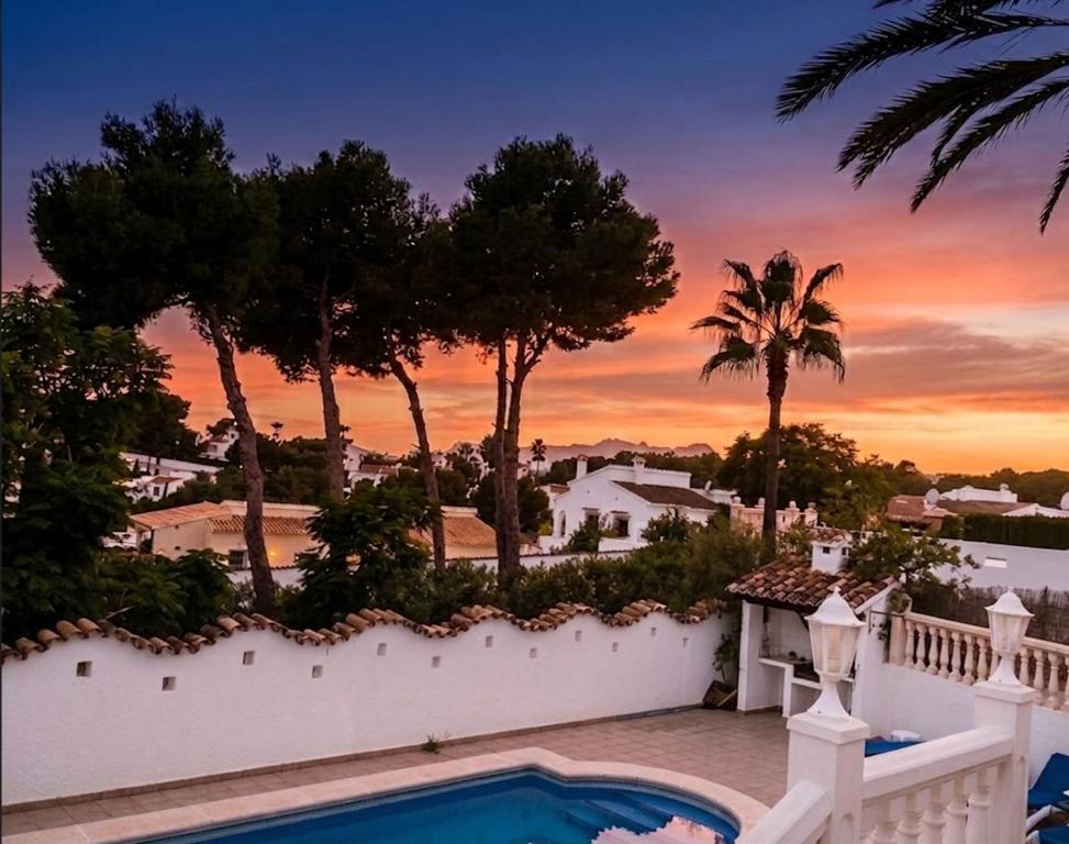 a house with a swimming pool and a sunset at Vista Portet, sleeps 10, Private Pool, Sea Views, Squash, 1 km from El Portet beach in Teulada