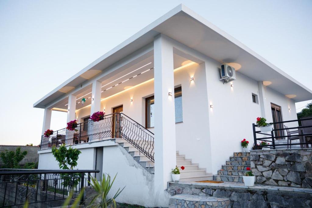 a white house with flowers on the stairs at Çifliku RSXH in Gjirokastër