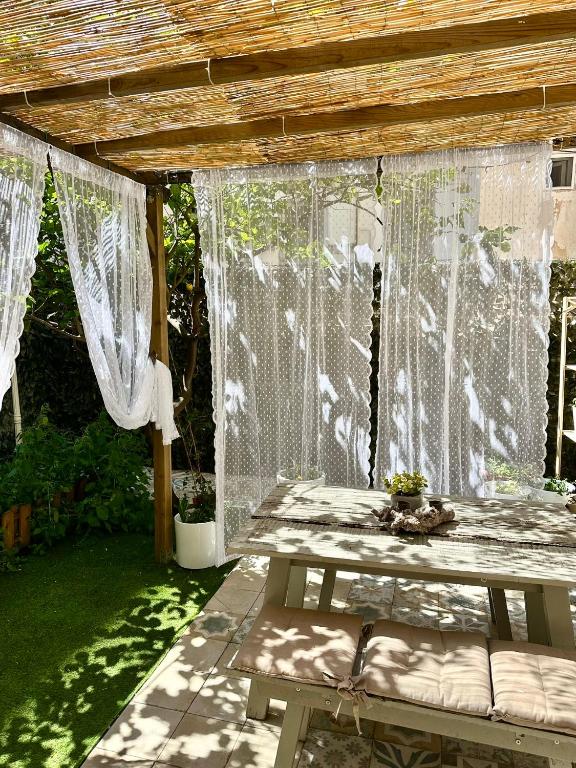 a pergola with curtains and a bench in a yard at Il giardino segreto in Taranto
