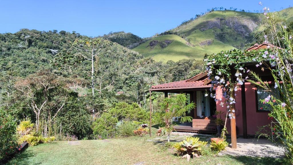 a small house in a garden with mountains in the background at Refúgio Orquídea Bambu - Lumiar in Nova Friburgo