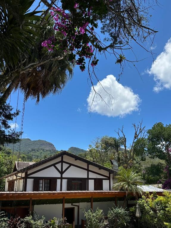 a house with a blue sky and flowers at Gaia Hotelaria in Teresópolis