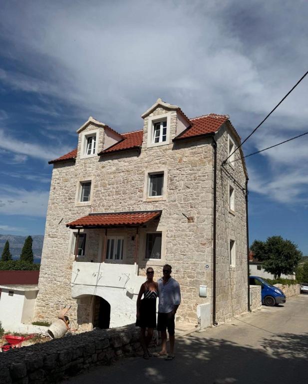two people standing in front of a building at Mirca with seaview - charming stonehouse in Mirce