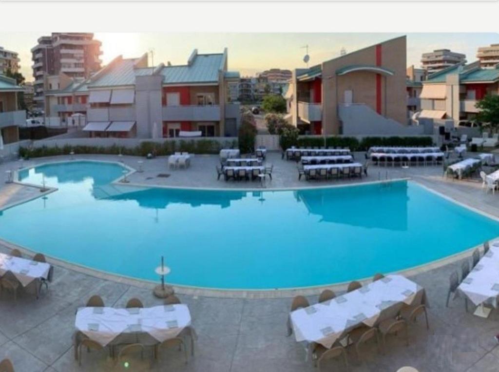 a large swimming pool with white tables and chairs at OLTRE CONFINE fronte mare in Marina di Montenero