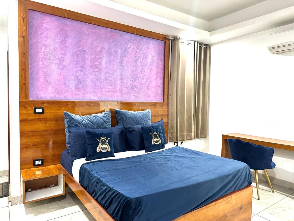 a bedroom with a blue bed with a purple screen at Blooming Inn in Gurgaon