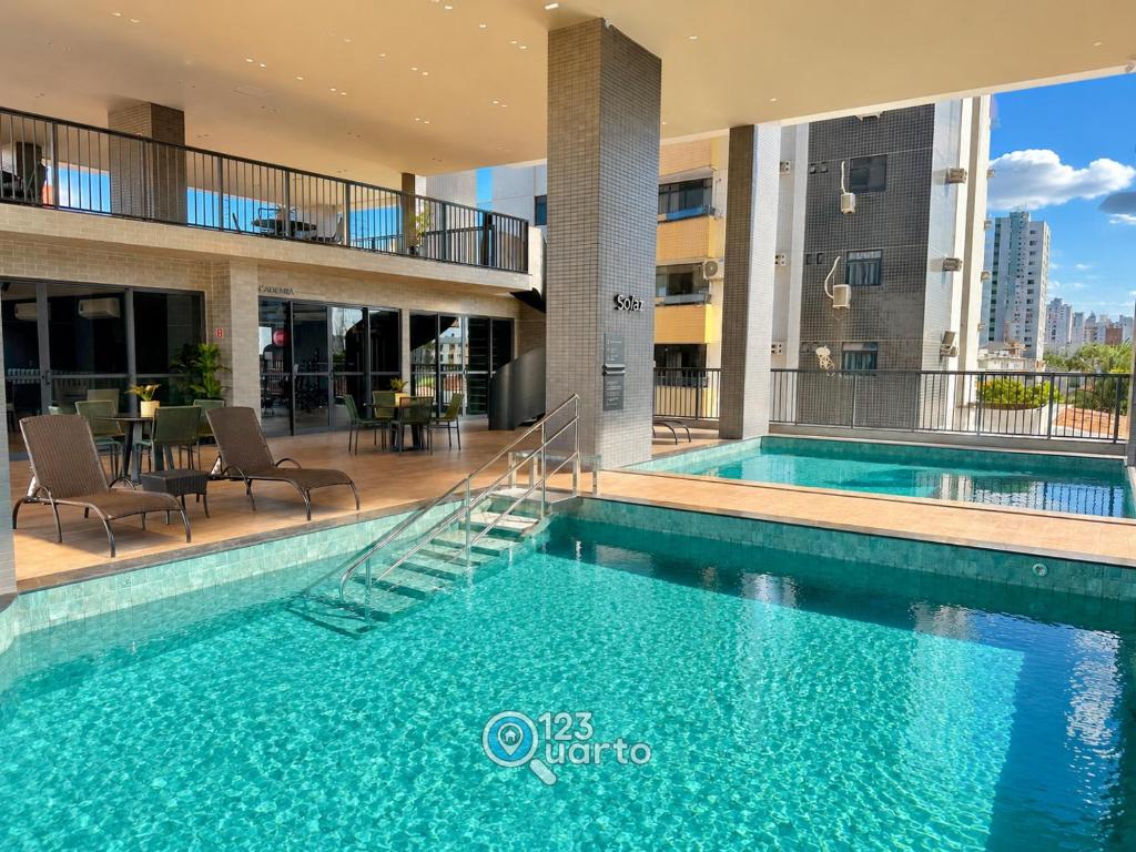 a swimming pool in a building with chairs and a table at Solaz Smart Living by 123Quarto in Tambaú