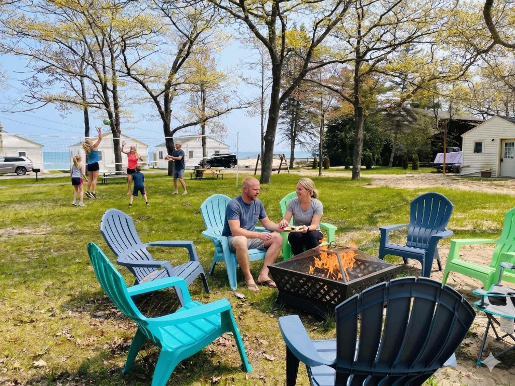 a man and woman sitting around a fire pit at Lake Huron Cottage 6 - 3 Bed 1 Bath in Lincoln Junction