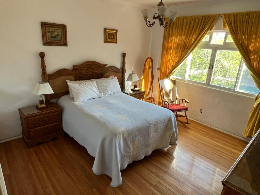 a bedroom with a large white bed and a window at Alma Roma, Hogar con Alma, B&B in Mexico City