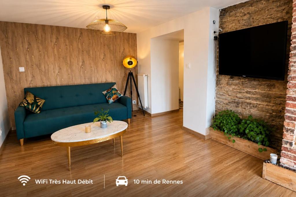 a living room with a green couch and a brick wall at Appartement T2 à la Campagne 10 min de Rennes in Corps-Nuds