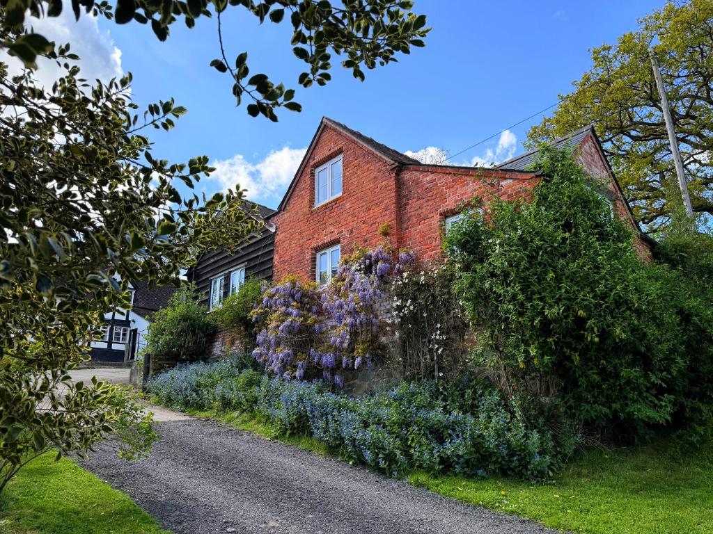 a brick house with purple flowers in front of it at Pandy Barn Berriew in Welshpool