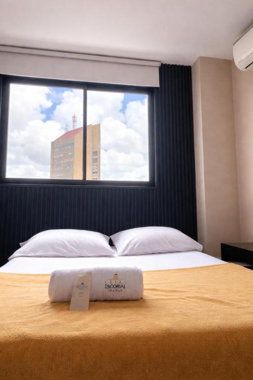 a bedroom with a large bed with a large window at Hotel Escorial Ibagué in Ibagué
