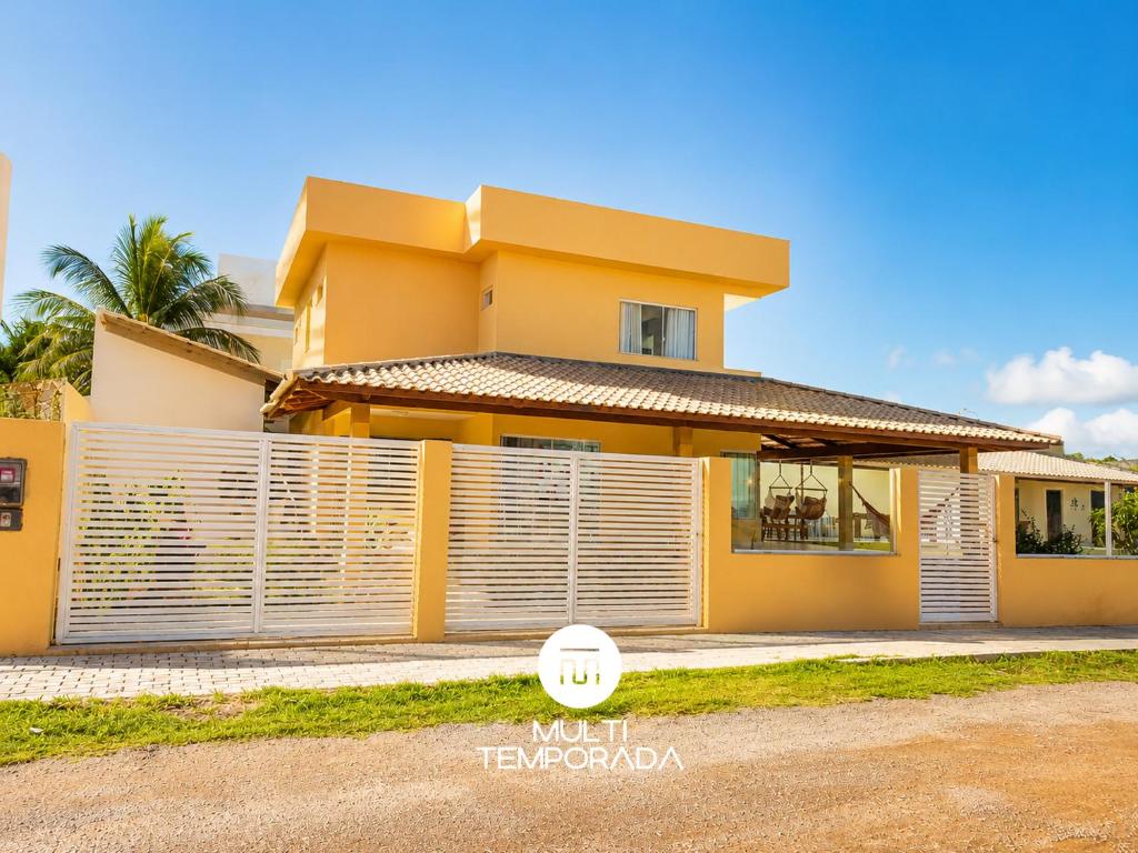 a yellow house with a fence in front of it at Casa Ilha do Sol - Vera Cruz/BA in Vera Cruz de Itaparica
