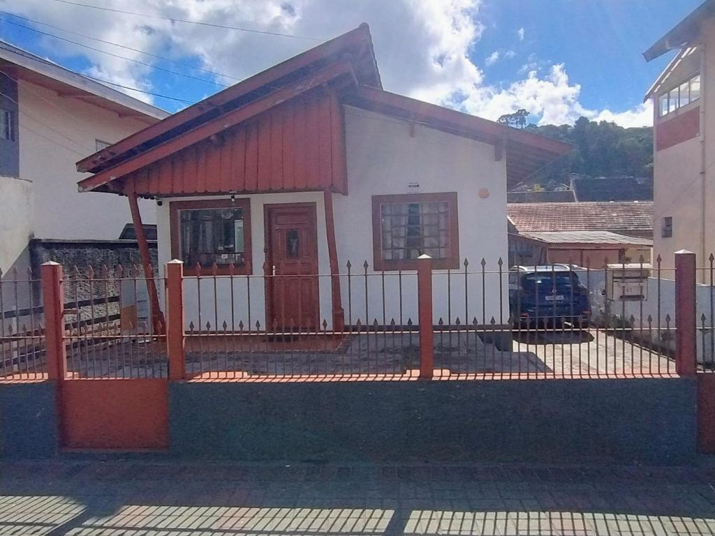 a small white house with a fence in front of it at casa charme e praticidade in Campos do Jordão