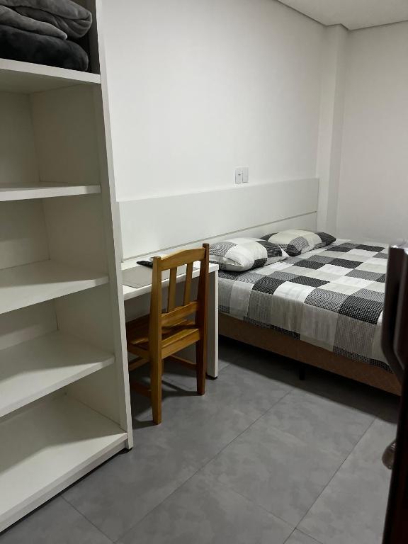 a bedroom with a bed and a wooden chair at Apart Hotel Eucalyptus in Telêmaco Borba