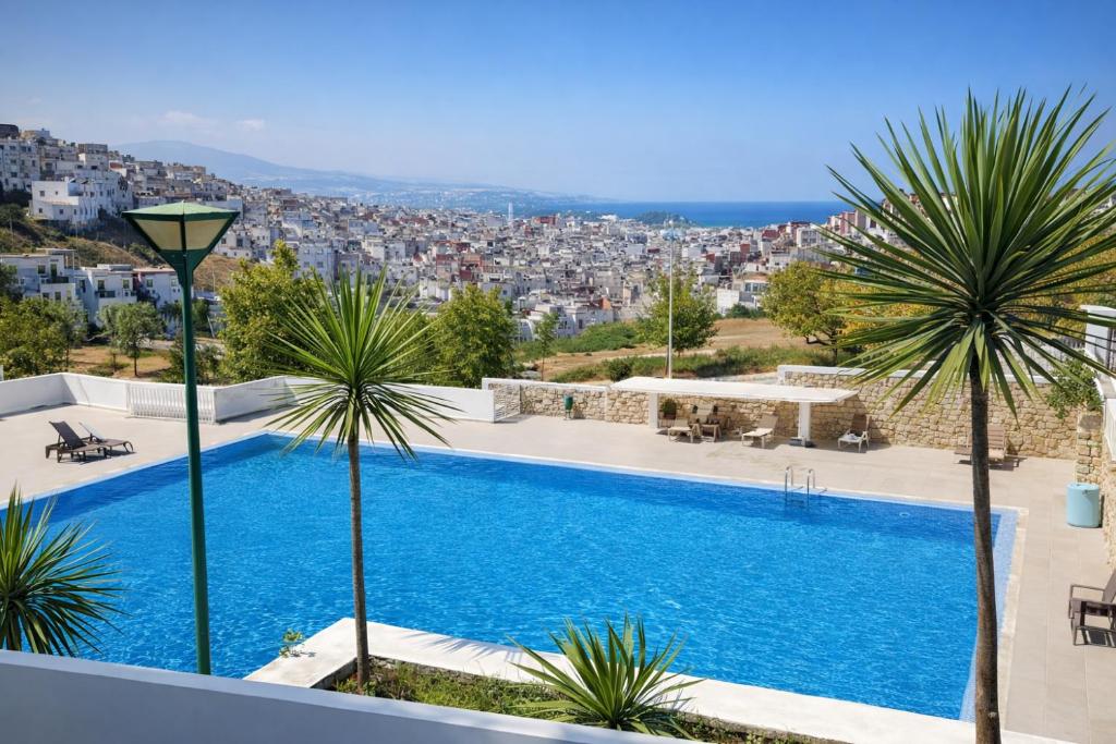 a villa with a swimming pool and palm trees at Panoramic View, Cozy apartment M'diq in M'diq