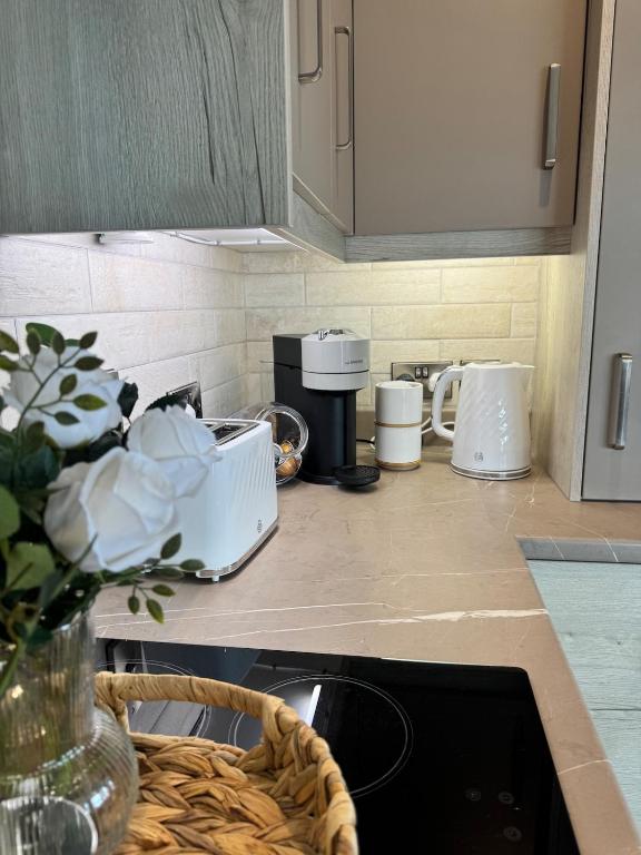 a kitchen counter with cups and a basket of flowers at Studio 7 in Dungannon