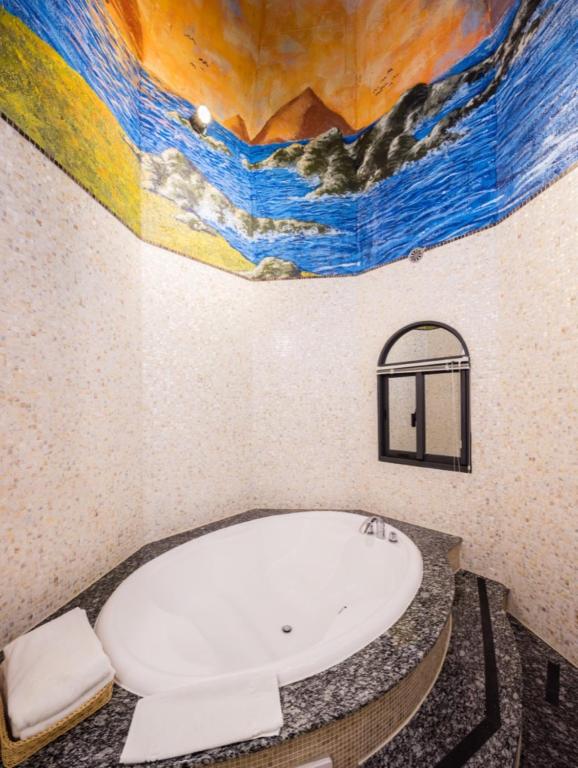 a bathroom with a bath tub with a painting on the wall at Zum Adler Castle B&amp;B in Jiaoxi