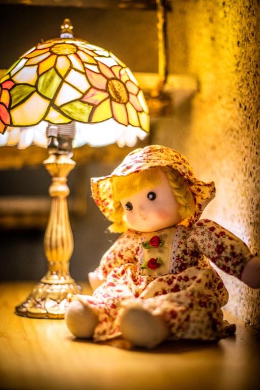 a doll sitting on a table next to a lamp at Zum Adler Castle B&amp;B in Jiaoxi