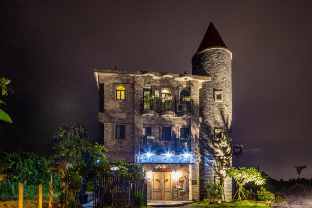 a large stone building with a tower at night at Zum Adler Castle B&amp;B in Jiaoxi