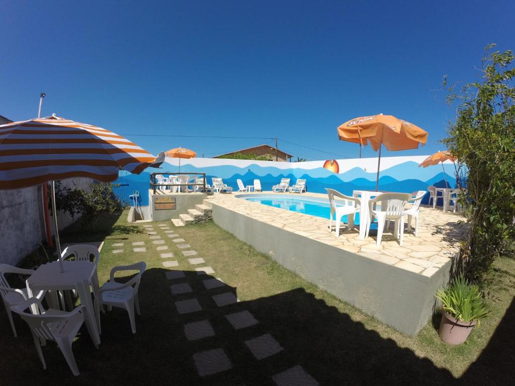 eine Terrasse mit Stühlen und Sonnenschirmen sowie einem Pool in der Unterkunft Pousada Orla do Sol in Prado