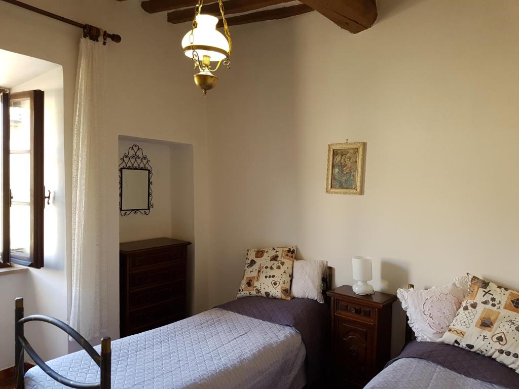 a bedroom with two beds and a chandelier at Le Pietre Antiche in Castiglione dʼOrcia