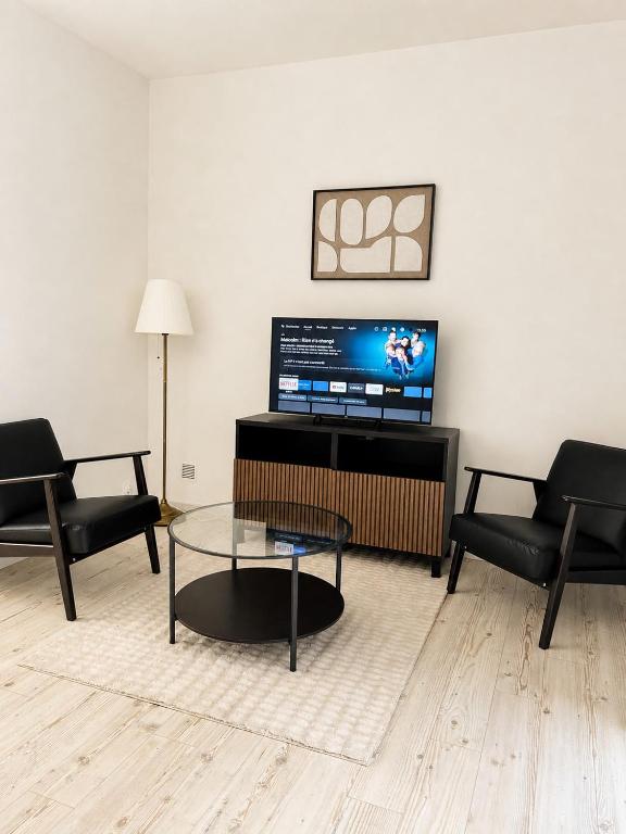 a living room with a tv and two chairs and a table at Studio Chaleureux in Langon