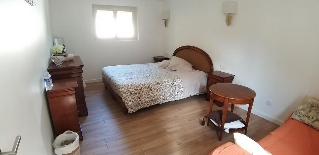 a bedroom with a bed and a table and a chair at Valérie GOUFFÉ Chambres d'hotes in Parigné-lʼÉvêque